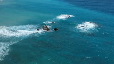 bellissima vista aerea delle molte sfumature dell'acqua blu limpido dei caraibi mentre le onde si rompono su grandi rocce