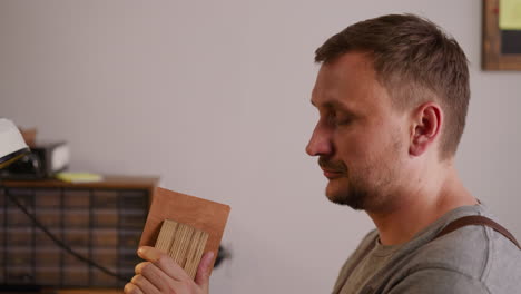 craftsman fixes piece of leather into wooden clamp in shop