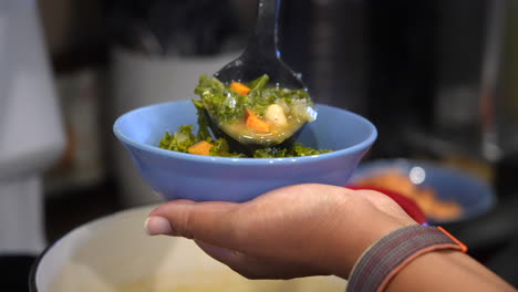 plating a bowl of kale and white bean soup - slow motion