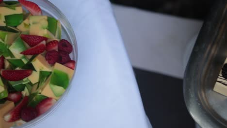 slow panning shot showing a tray of blackberry deserts and bowl of fruit