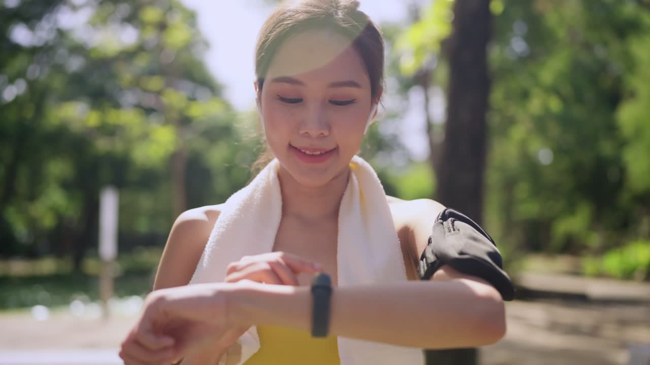 cheering asian smile female sport woman athlete on a morning run rejoices victory,female checking time on his wrist watch in fitness clothes say yes for jogging running beat the score hersellf workout