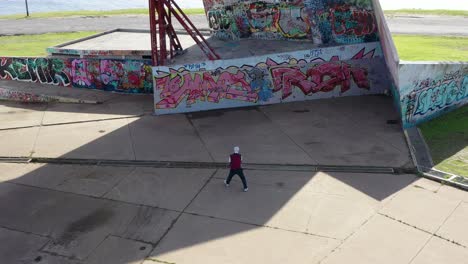 man playing fronton tennis on a graffitied wall, public park, modern urban amphitheater