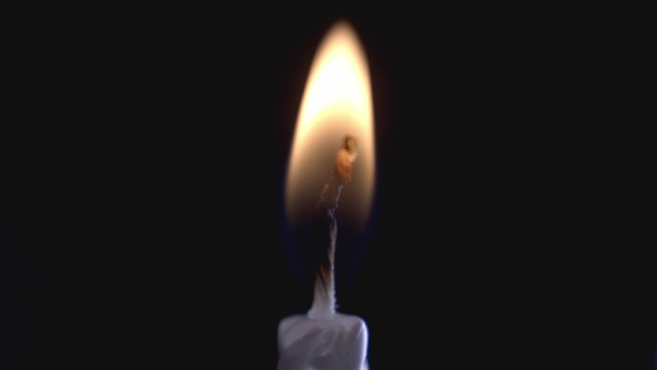 Una luce di candela su sfondo nero. - primo piano