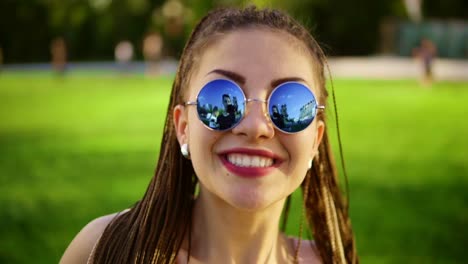 una mujer hermosa con vaqueros y gafas de sol escuchando música y bailando.