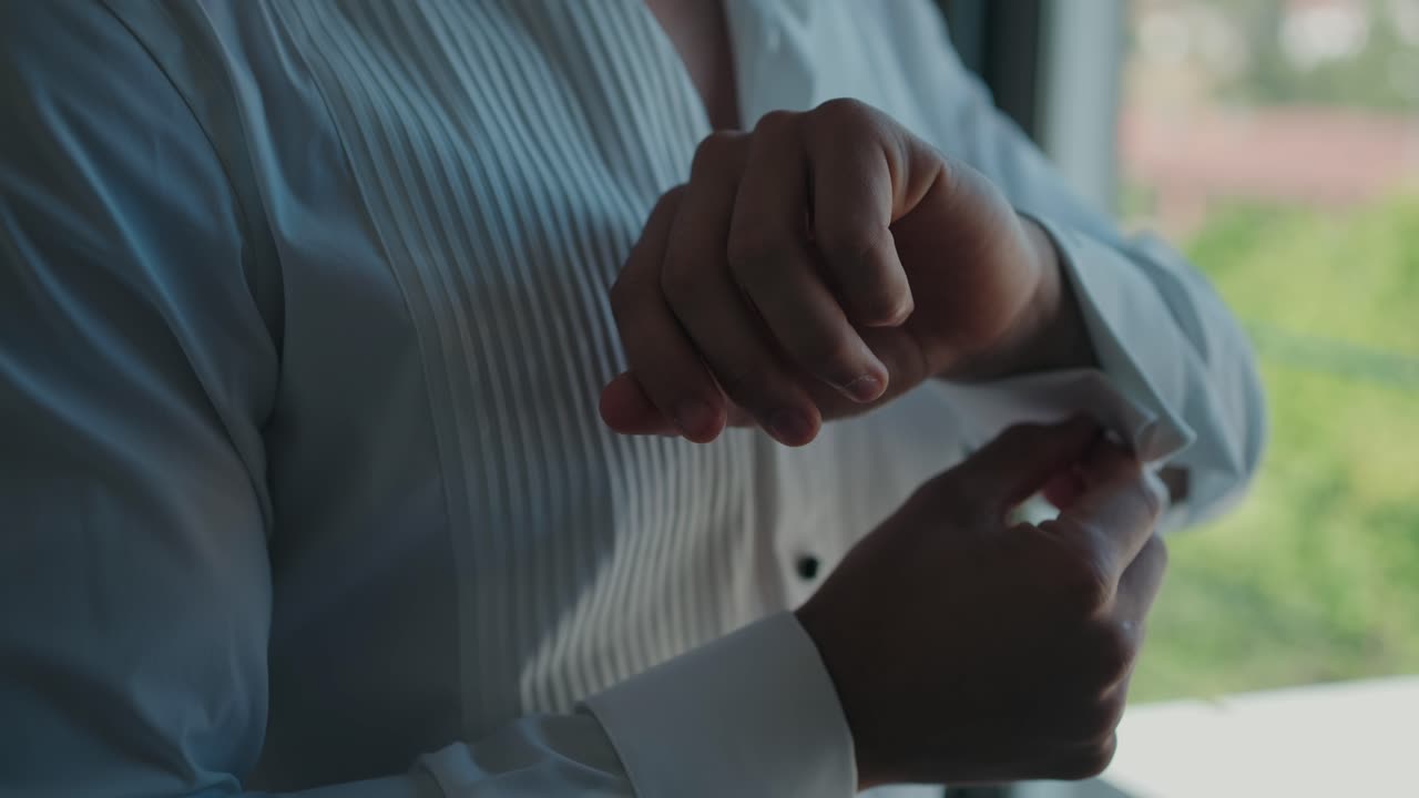 close up pengantin pria mengancingkan manset pada kemeja putih formal