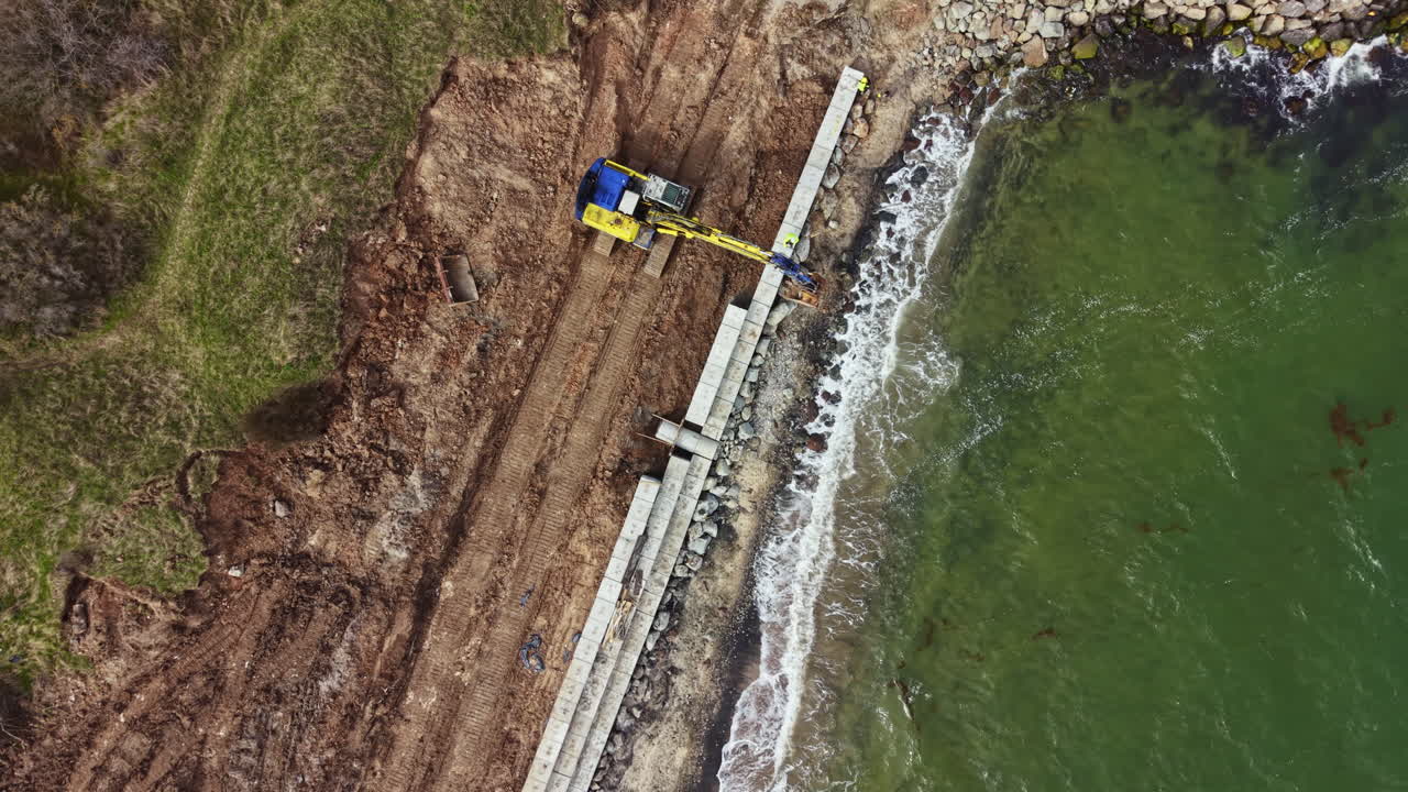 Operai edili costruiscono una barriera frangiflutti lungo la costa per proteggere la terra dall'erosione durante il giorno