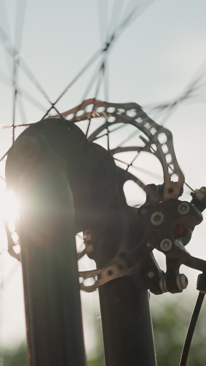 primer plano de una rueda de bicicleta girando a diferentes velocidades, con la luz del sol creando un efecto cautivador alrededor de la rueda, el suave borrón del fondo mejora la sensación dinámica