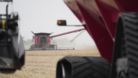 combine harvester harvesting grain crops from a farm field on a dusty day