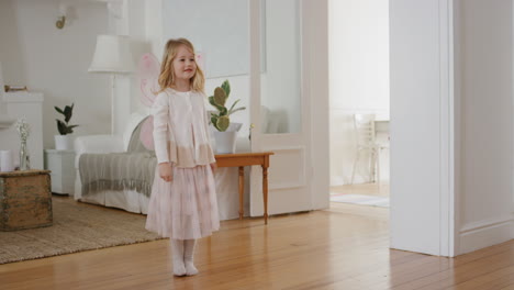 Niña-Feliz-Bailando-Juguetonamente-Haciéndose-Pasar-Por-Bailarina-Niña-Graciosa-Divirtiéndose-Jugando-A-Disfrazarse-Usando-Un-Traje-De-Ballet-Con-Alas-De-Hada-En-Casa-4k