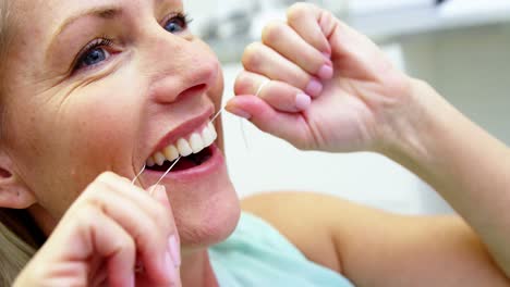 mujer lavándose los dientes con hilo dental