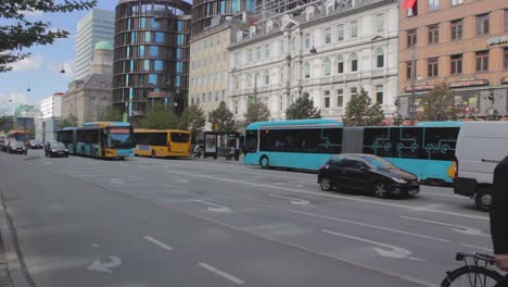 rush hour traffic on busy road in city center with buildings on background. cars and public bus crossing the street and  stop at red traffic light, copenhagen, denmark.