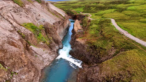 river flowing in the crack in the mountains. top view on the rocks covered with green moss. iceland wild nature.