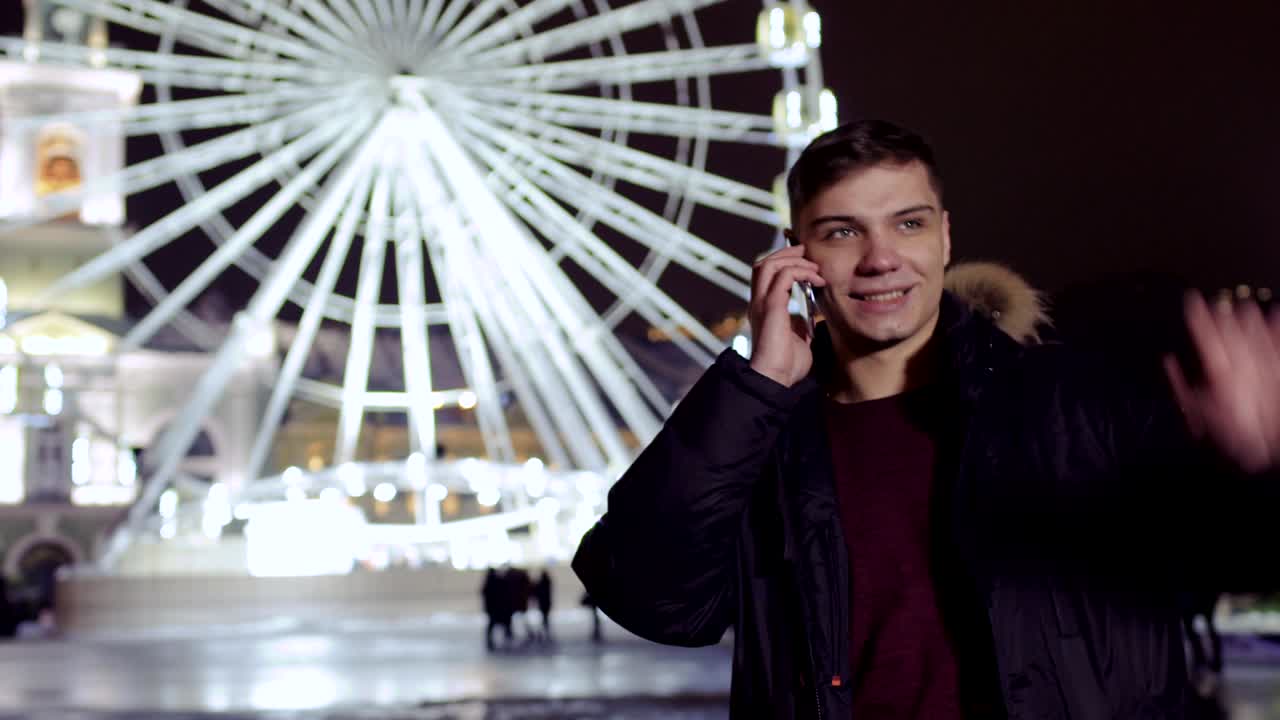 젊은 남자가 전화로 이야기하고 페리스  근처의 친구를 기다리고 있습니다.