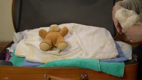 padres empacando una maleta con ropa y ositos de peluche, plano medio