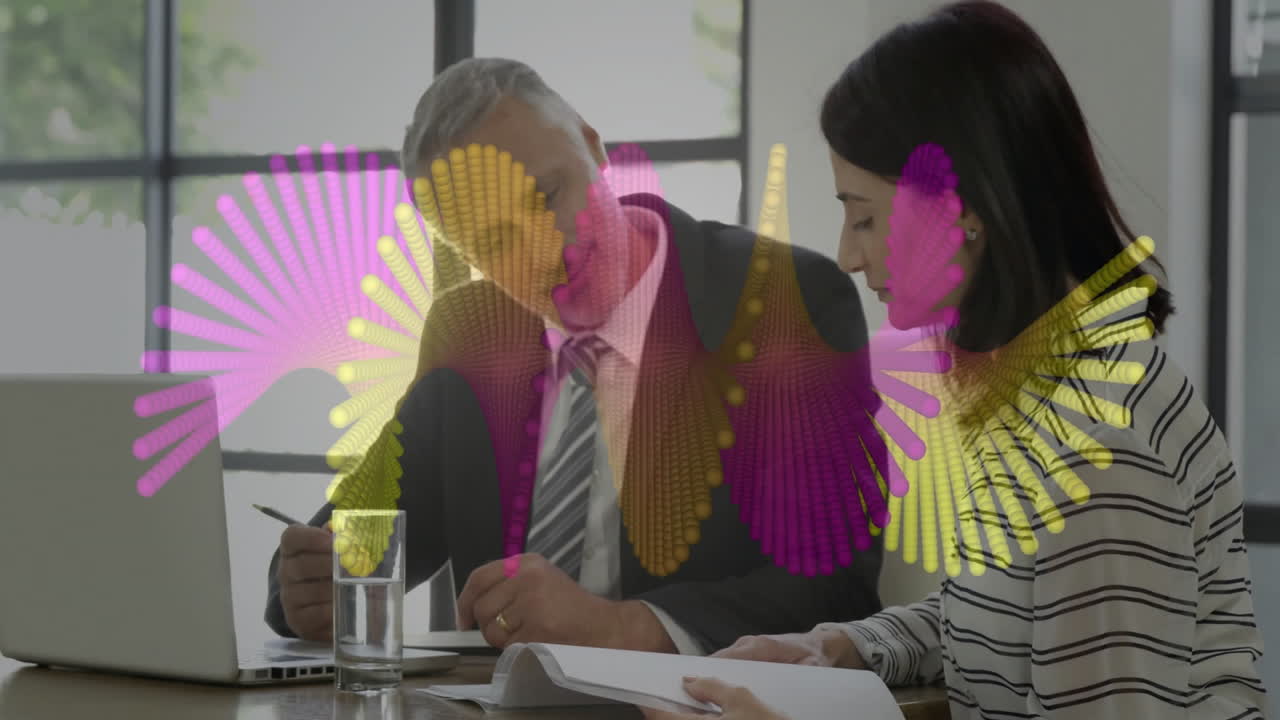 man signing contract while woman reviewing documents in business office showing colorful data chart