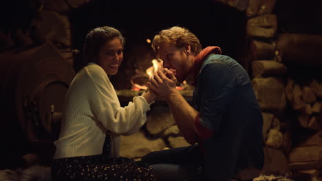 loving couple warming fireplace in country house. boyfriend girlfriend kiss hand