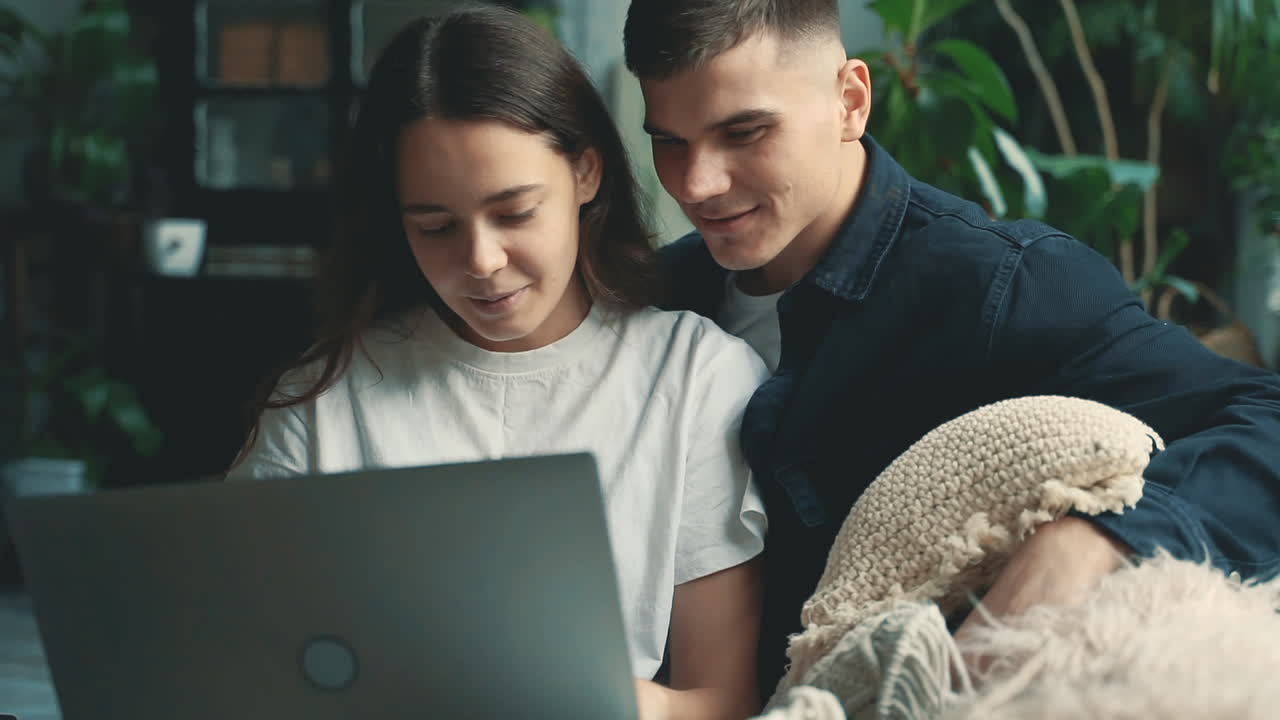 jóvenes amantes mujer y hombre usando una laptop juntos