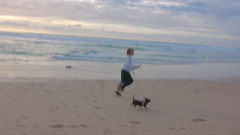mujer corriendo en la playa con su perro al atardecer
