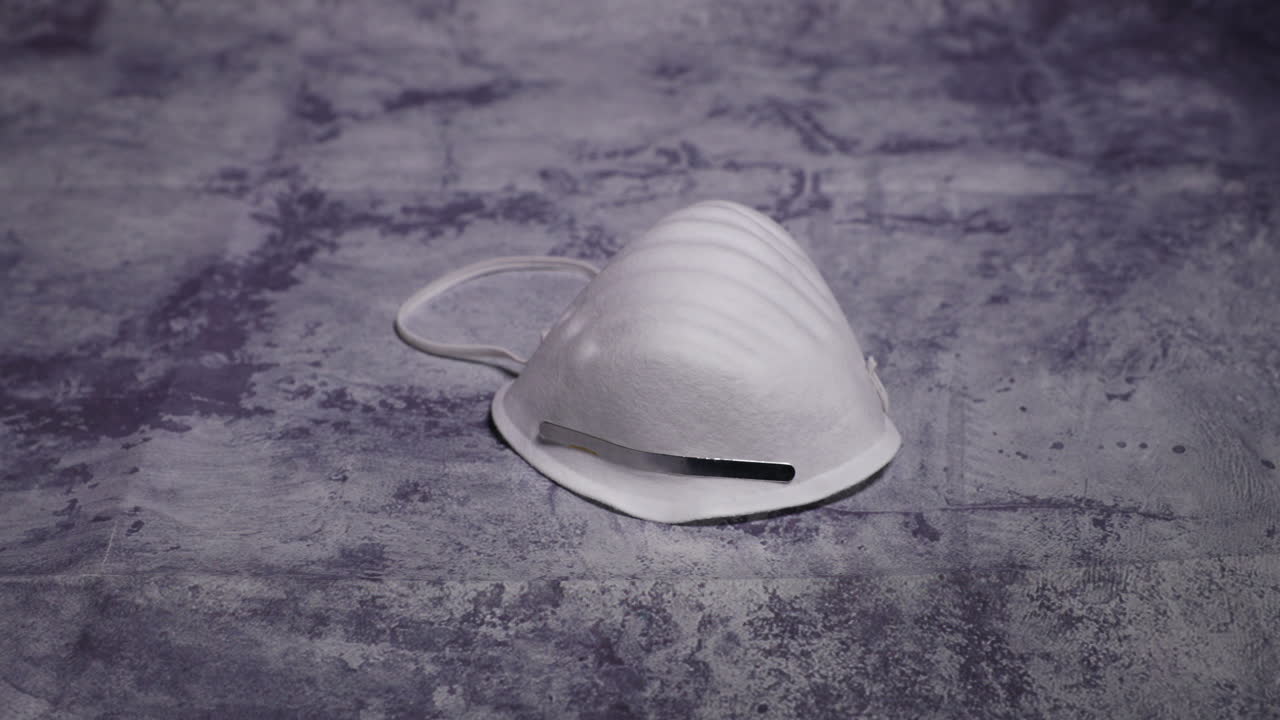 Men's hands first person view taking and putting protective face mask on camera white mask from threat like corona Covid-19 virus protects mouth and nose from dark black board capture in 4k 60fps