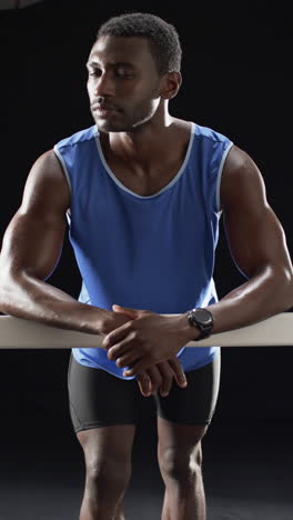 vertical video: strong and fit athlete in sportswear leaning on bar, looking determined