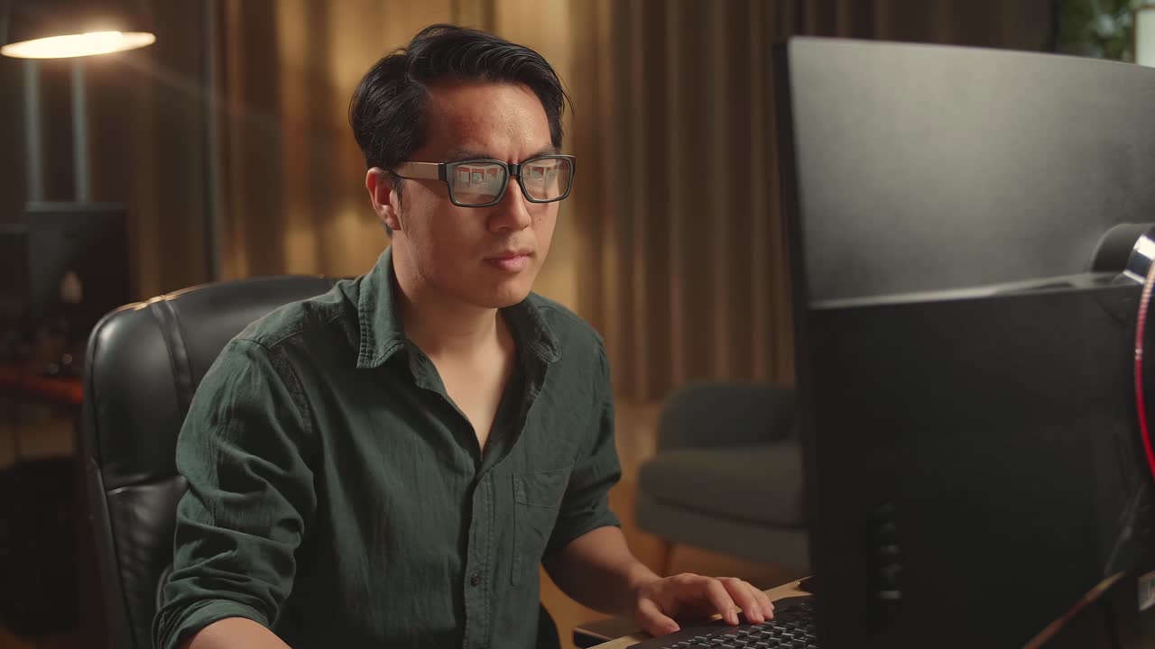 Asian Male Drinking Coffee While Works On His Personal Computer With Big Display, He Works At Night