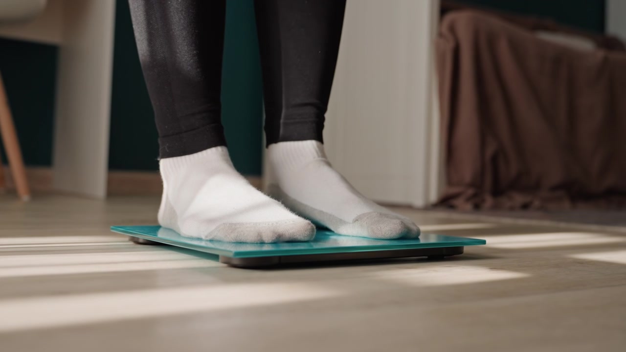 Mindful weight tracking at home. Walking carefully onto transparent scale shows stability. Engaging in mindful movement and precise weight observation promotes balanced health and stability