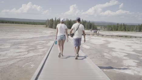 two people walking on boardwalk at grand prismatic springs in yellowstone national park