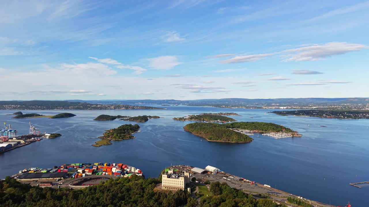 Farbenfrohes Containerterminal, bewaldete Inseln und ruhige Gewässer des Oslofjords, aus großer Höhe an einem klaren Sommertag gesehen.