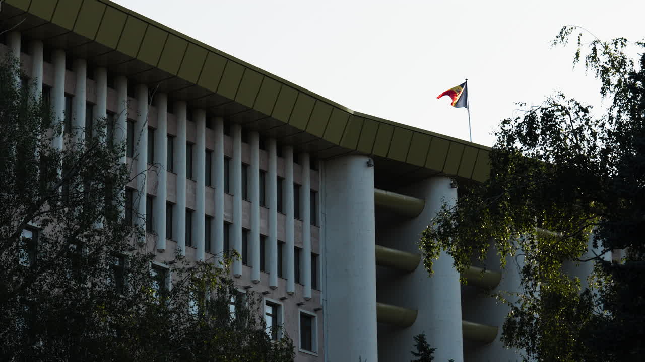 Moldova’s Parliament building in Chișinău with the national flag proudly waving on a bright, clear day. Focus on architecture, patriotism, and political identity.