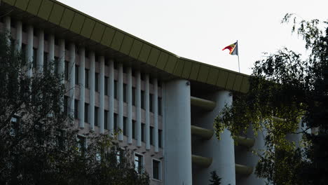 moldova’s parliament building in chișinău with the national flag proudly waving on a bright, clear day. focus on architecture, patriotism, and political identity.