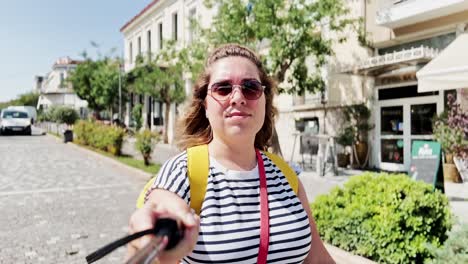 woman preparing her selfie stick for filming, athens, greece