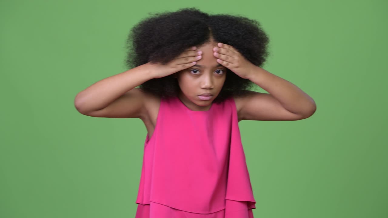 Giovane ragazza africana carina con capelli afro che ha mal di testa