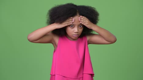 una joven africana con cabello afro que tiene dolor de cabeza.