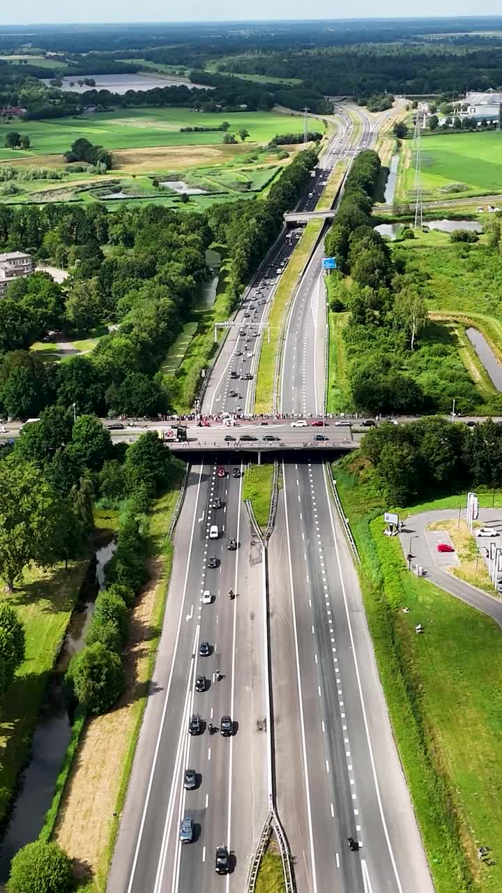 Aerial view of a highway with traffic and people gathered on an overpass bridge
