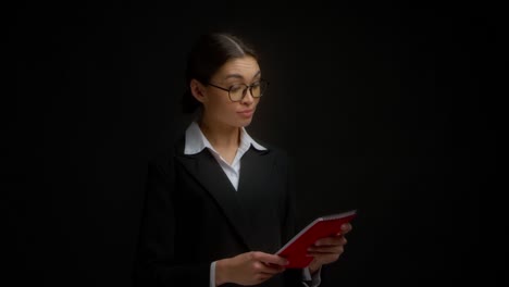 woman boss with glasses is handed a red notebook. isolated on a black background