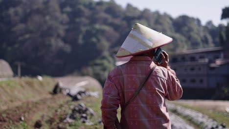 person in conical hat working in a rural farm field