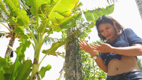 enjoying the rainbow, a sweet asian woman playfully enjoys cool outdoor shower.