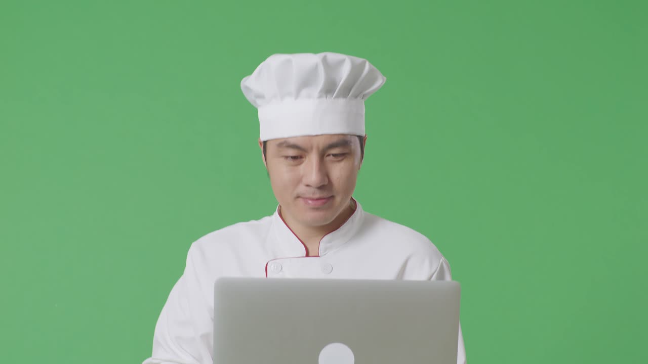 녹색 화면 배경 스튜디오에서 는 동안 노트북을 사용하는 아시아인 요리사