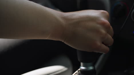 woman's hand reaches into frame and shifts gears on manual transmission