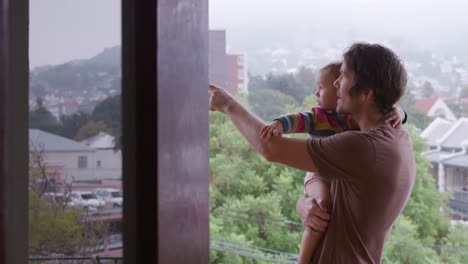 hombre caucásico con bebé mirando lejos en casa