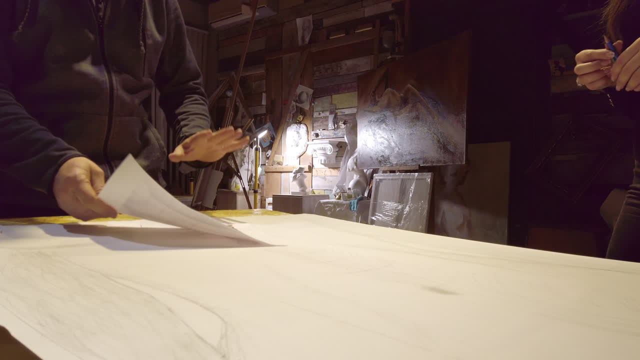 Man supervising a woman sketching on a canvas at an art gallery workshop