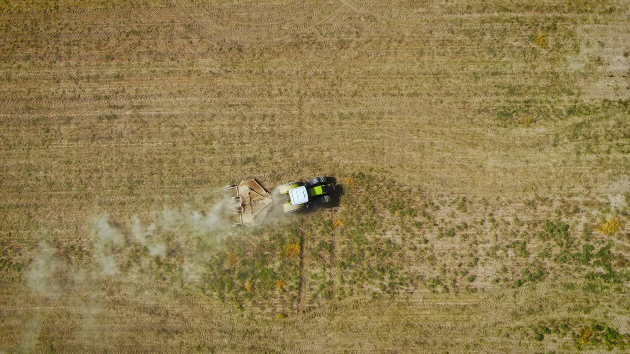 Trator agrícola ceifando grama no campo em Almaty, Cazaquistão - vista aérea de cima.