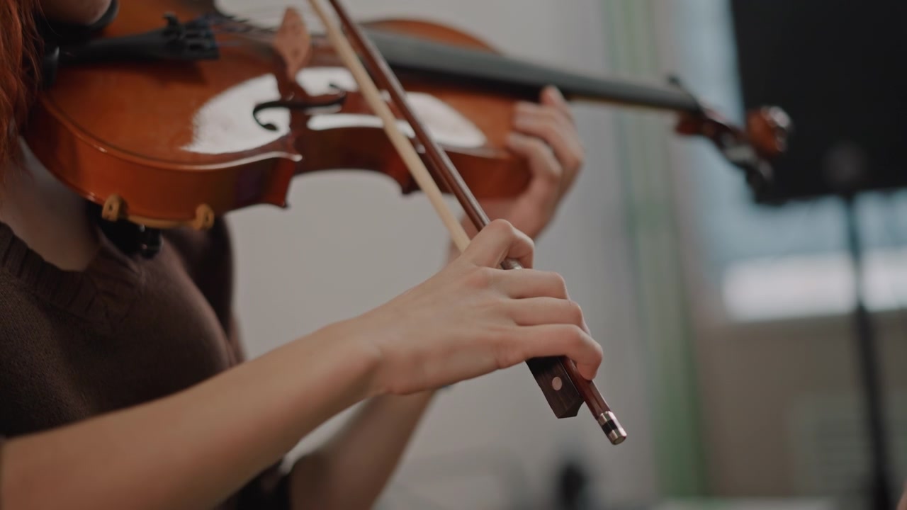 Closeup violin lesson with hands guiding technique and bow placement in intimate classroom setting, instructor correcting finger position, student practicing scales, warm natural light