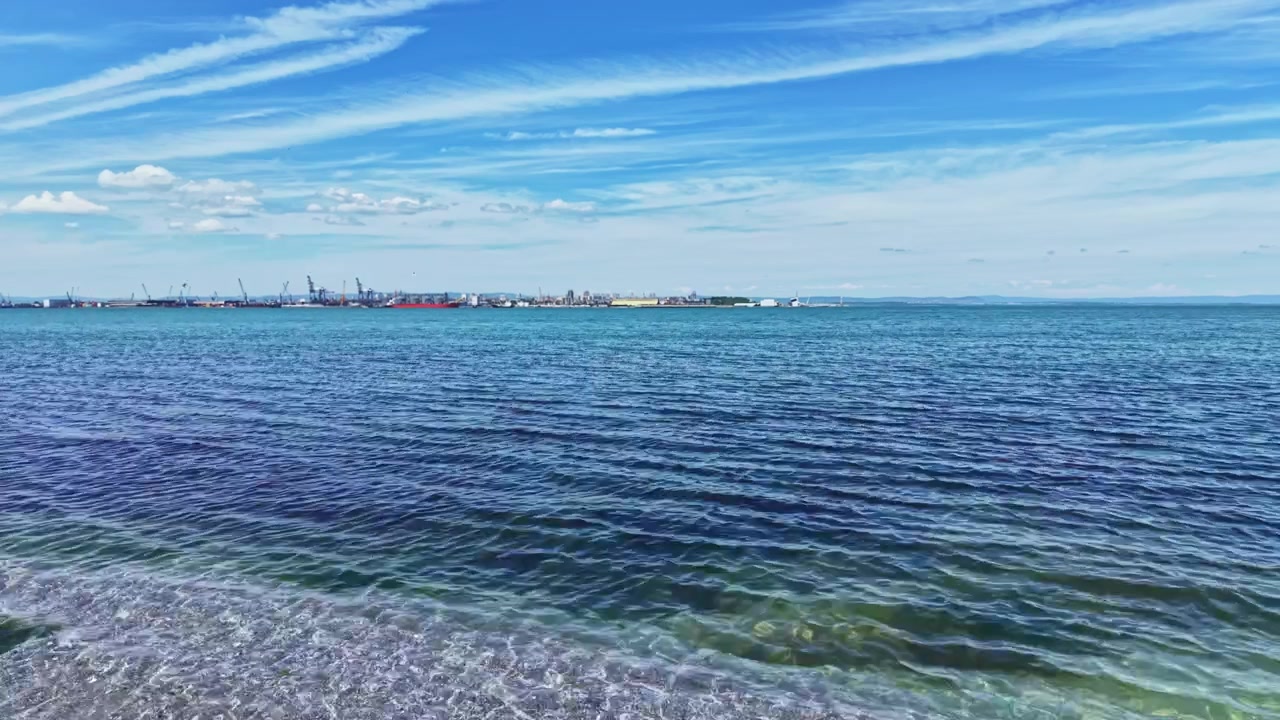 Ruhiges maritimes Panorama. Friedliche Küstenszene mit sanften Wellen und entfernten Schiffen. Stille Küstenlandschaft mit weitem blauem Himmel und langsam fahrenden Schiffen in der Ferne.