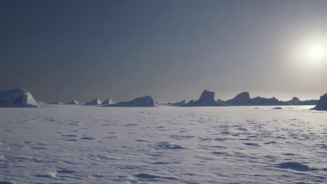 Vidvinkelbillede af et stort, snedækket landskab under en klar himmel, der fanger fjerne isformationer