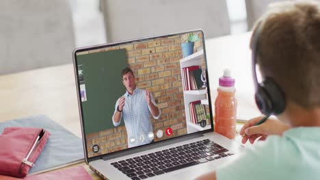 composition of caucasian boy on laptop online learning with caucasian male teacher