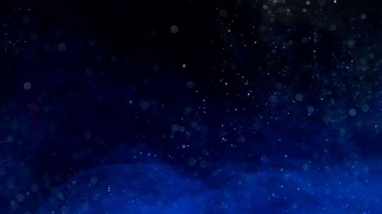 추상적인 다채로운 파란색 테일 금속 잉크 물방울 화학 물질과 빛나는 입자가 검은 sf 배경에 액체 물에서 흐르는 느린 동작