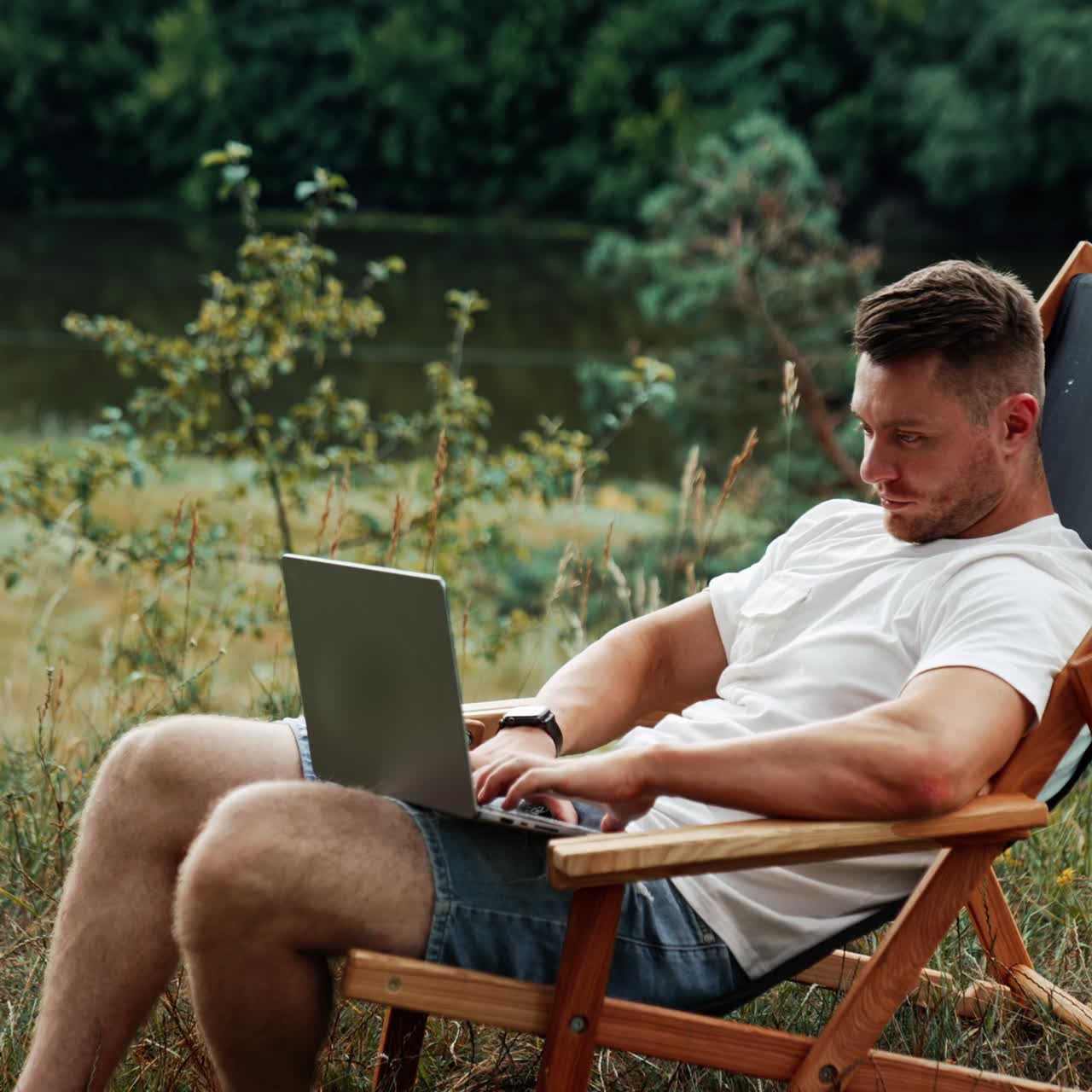 Man sitting peacefully in the chair among the nature. Freelancer types on his laptop working remotely