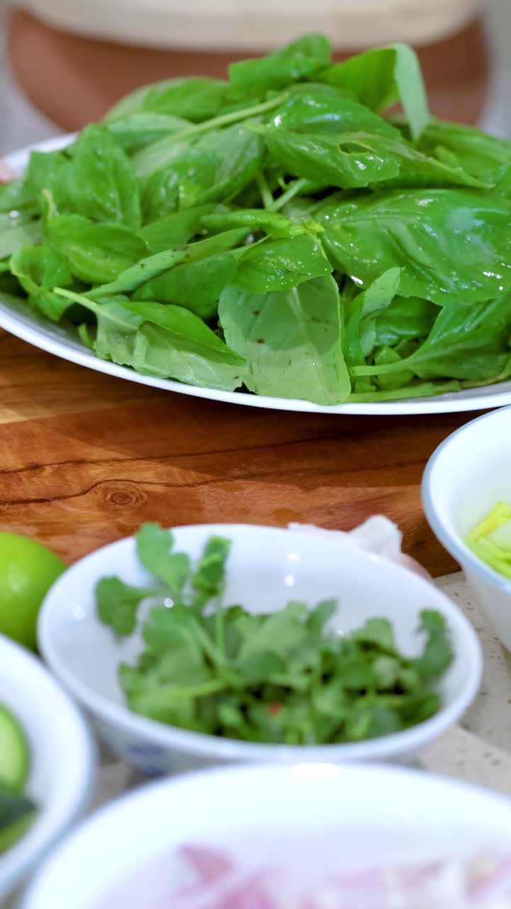 Una persona sistema foglie di basilico fresco su un piatto in un ambiente cucina ben illuminato.