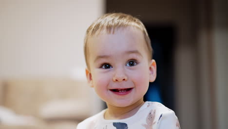happy healthy caucasian toddler smiling adorably to the camera. kid is joyful for getting a toy. close up portrait.